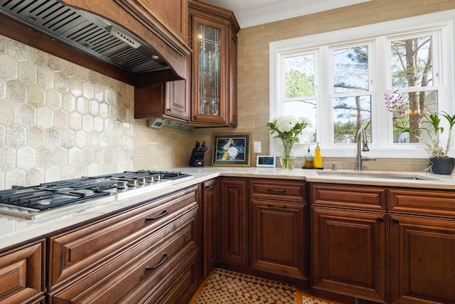 A kitchen with wooden cabinets and tiles walls.