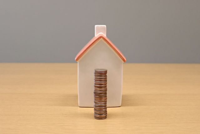 coins stacked in front of a miniature house