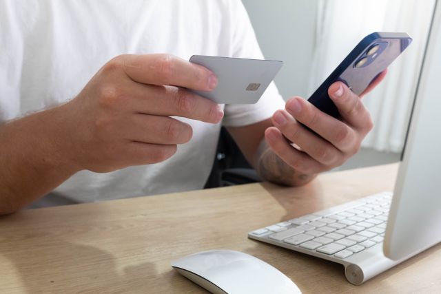 person holding credit card and phone